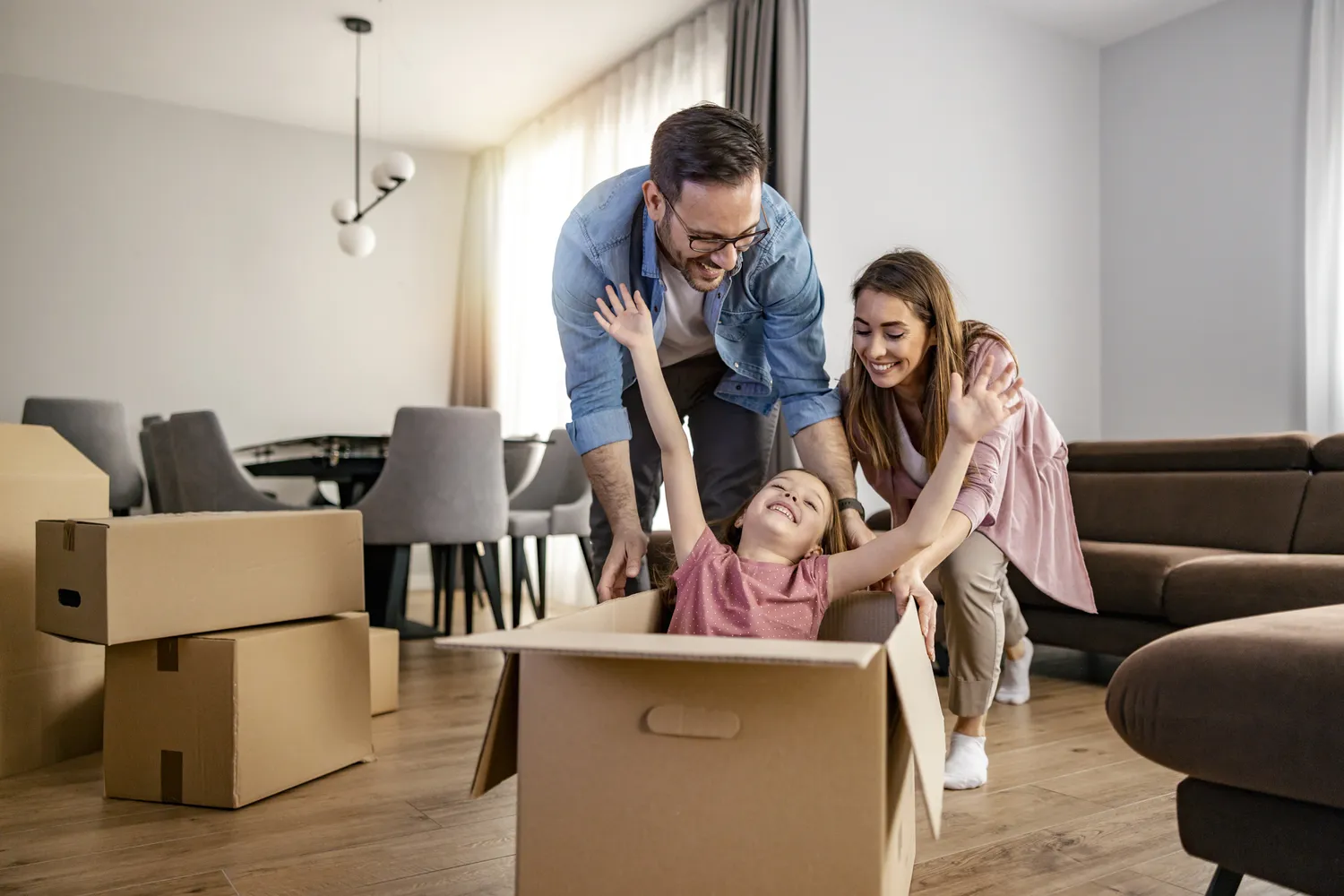 Herzensnah by Tanita Englisch - Familiäre Unterstützung -Eine Familie spielt in einem Wohnzimmer inmitten von Umzugskartons.